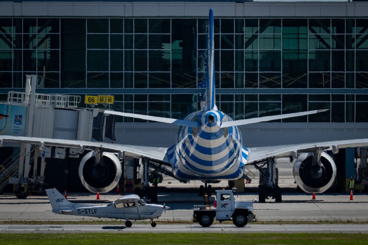 A small white plane is parked behind a large blue and white plane outside.