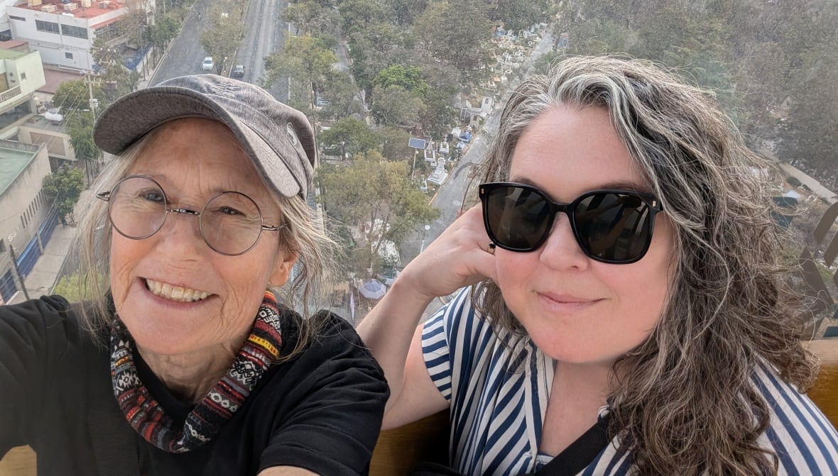 Two smiling women pose for a selfie in a cable car.