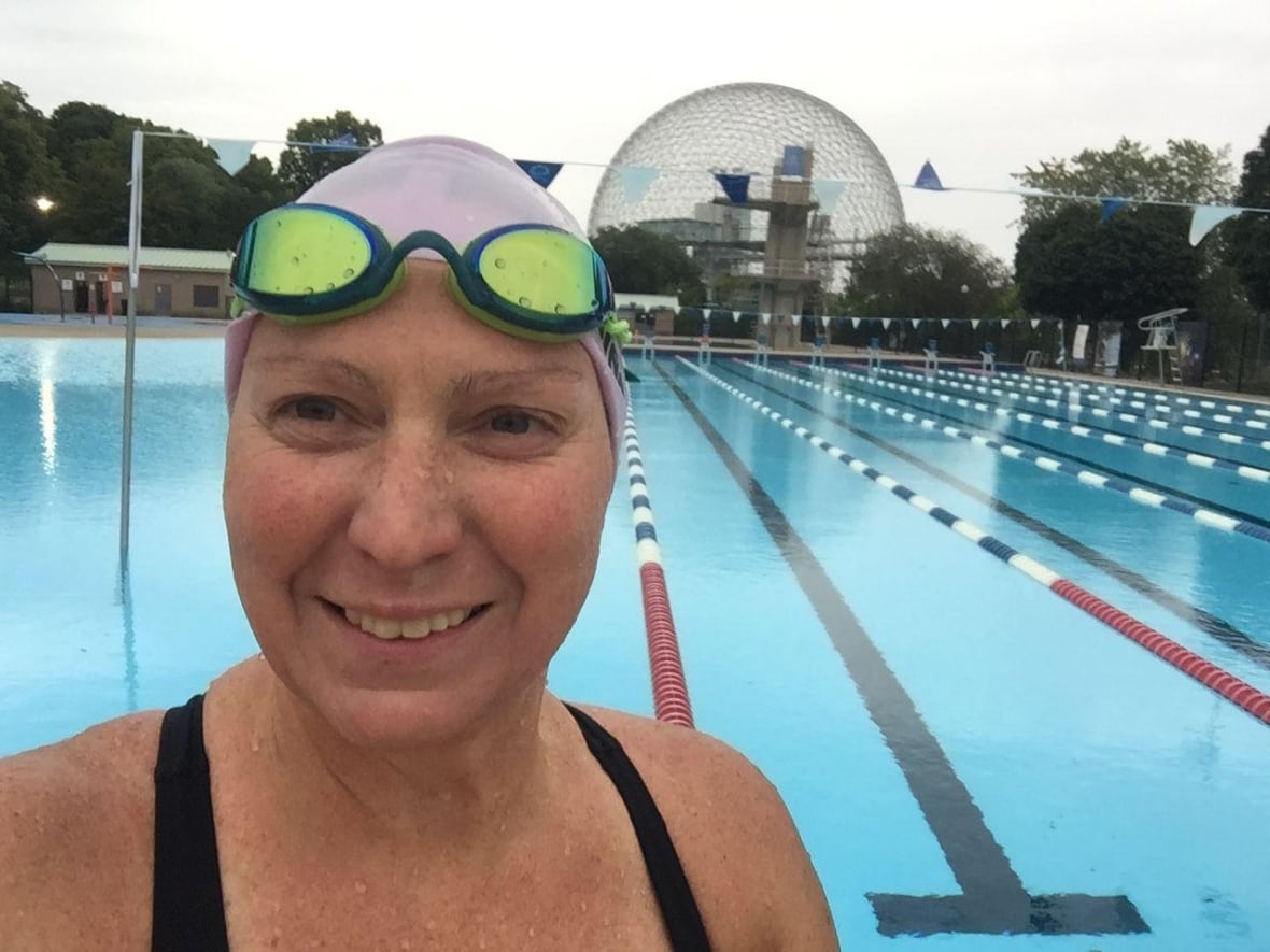 A woman standing in fornt of a pool smiles at the camera
