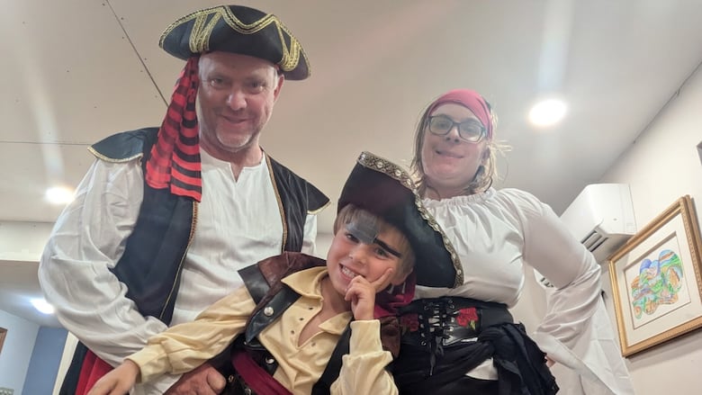 A family of three dressed as pirates. A white man, a white woman and a 4-year old white boy.