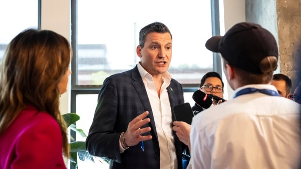 A man with short grey hair speaks to reporters