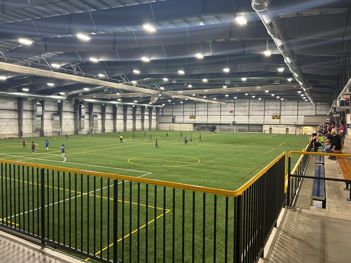 A group of children play in an indoor soccer field.