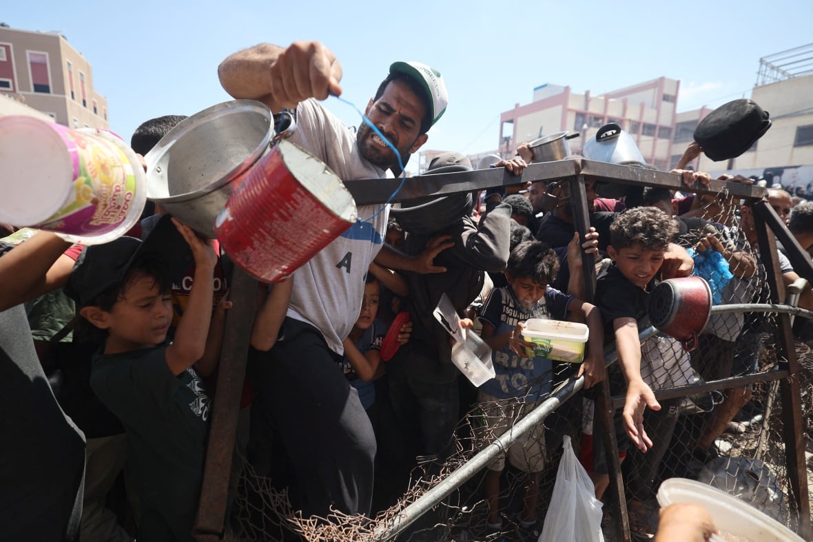 People scramble to obtain food at an aid distribution site.