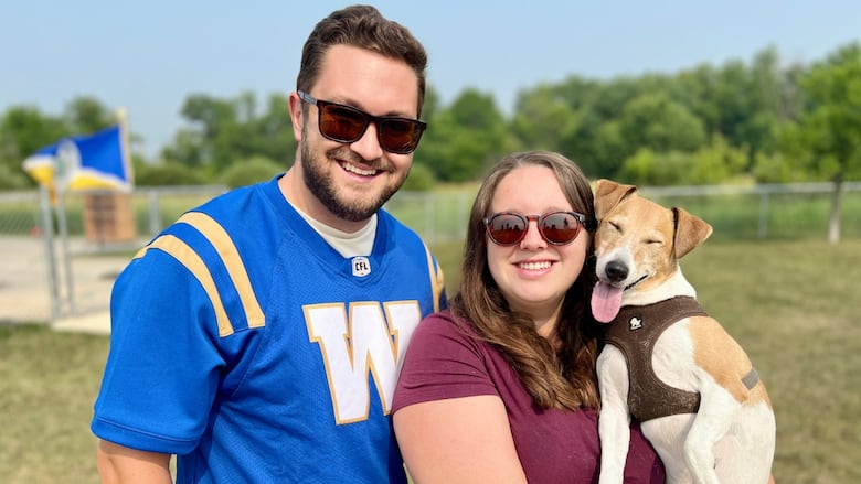 A couple with a dog smile for a picture.