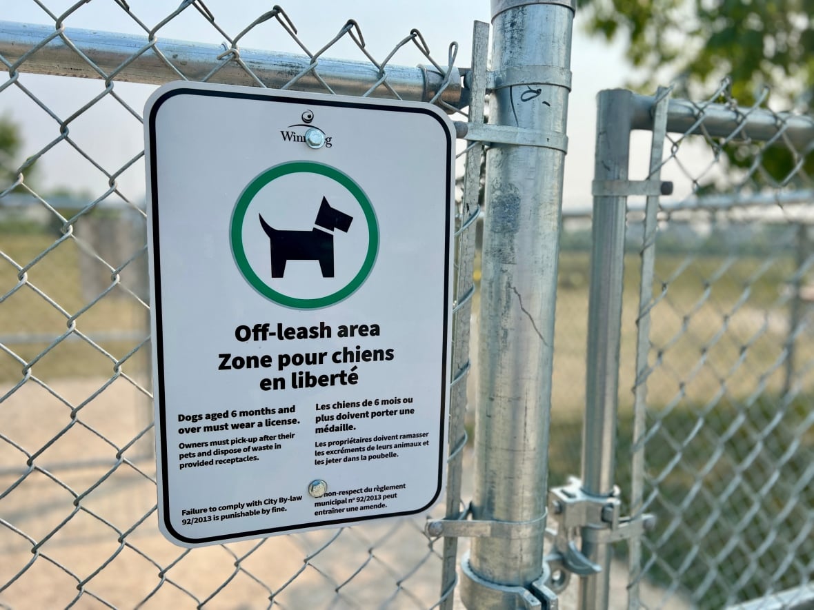 A sign with a dog in a green circle is on a fence. 