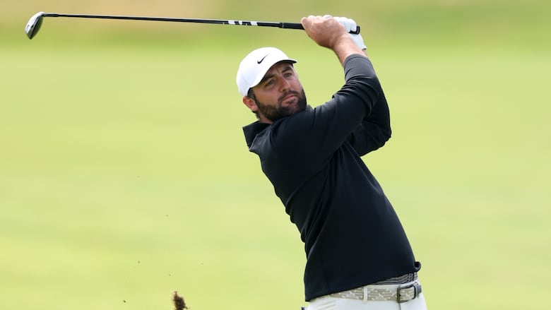A male golfer plays a shot, swinging his club into the air.