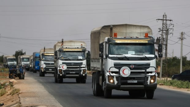 A convoy of vehicles loaded with food and other aid is en route to Sweida on the international highway in rural Daraa province, Syria, Sunday, July 20, 2025, heading to the city of Busra al-Sham. A convoy of trucks travels on a paved road.