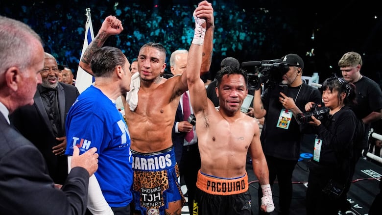 Two male boxers hold up each other's arms in celebration inside the ring.