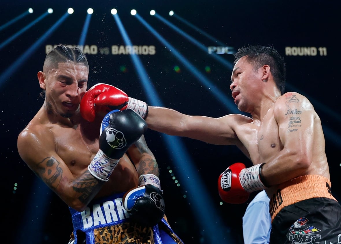A male boxer lands a straight right punch as spotlights shine down in the arena.