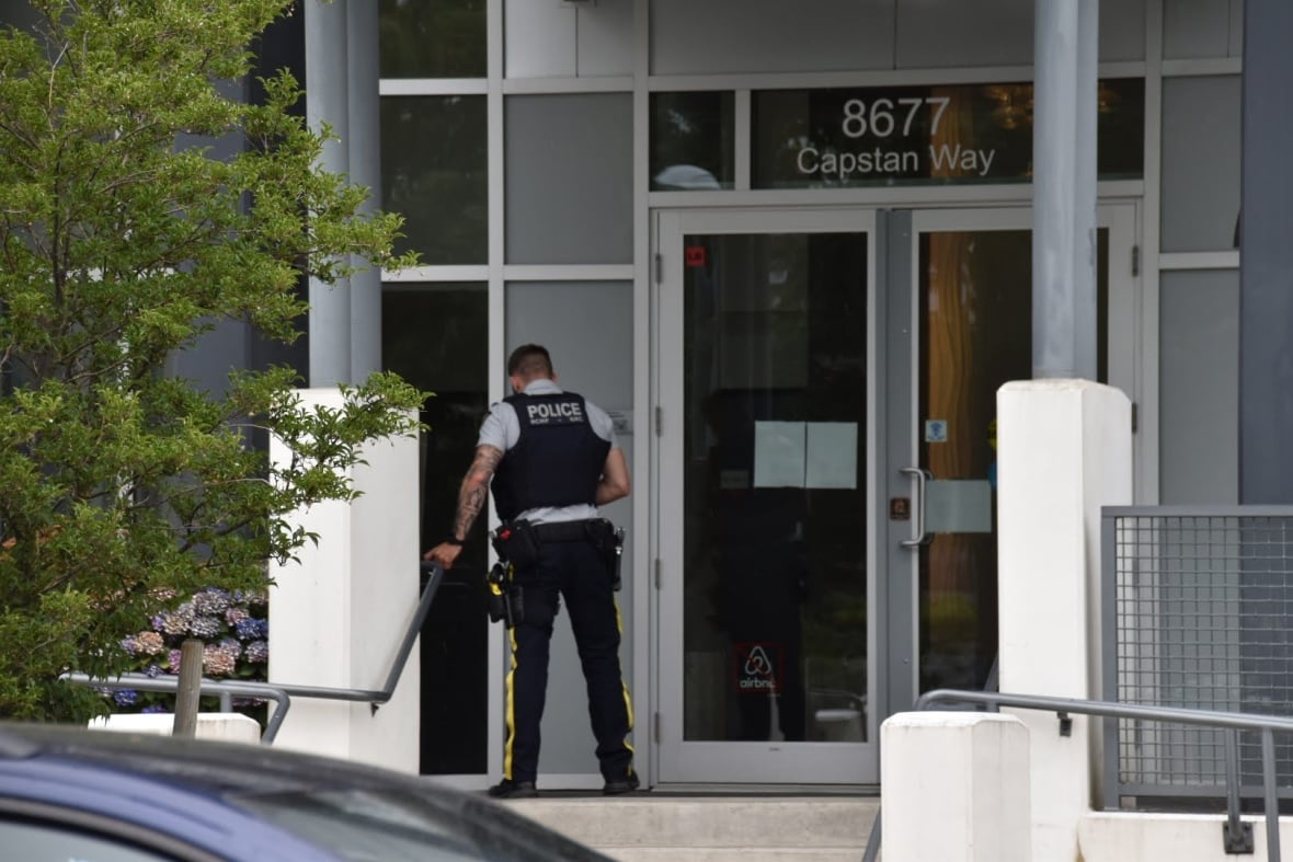 A police officer leans on the railing leading to an apartment building entrance.
