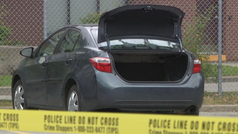 a car is weeing with the open trunk, surrounded by yellow police tape