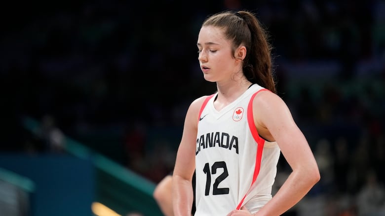 A women's basketball player walks off the court.