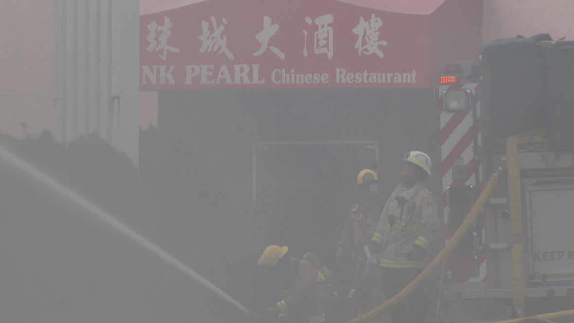 Los bomberos trabajan con humo espeso frente al restaurante chino Pink Pearl porque están luchando contra un incendio en el edificio vecino.