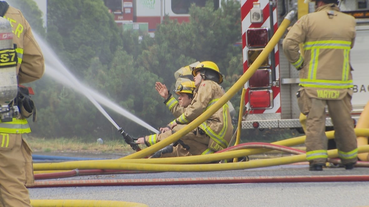 Firefighters operate a hose line while battling a fire.