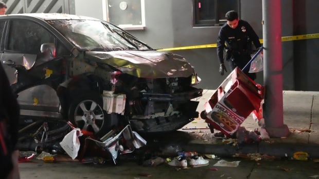 A vehicle sits on the sidewalk after ramming into a crowd of people waiting to enter a nightclub along a busy boulevard in Los Angeles early Saturday, July 19, 2025, injuring multiple people. A police officer inspects a badly damaged vehicle.