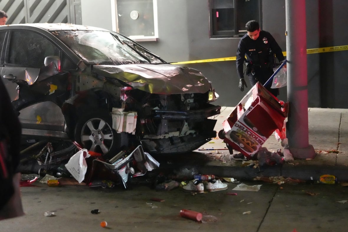 A police officer inspects a badly damaged vehicle.