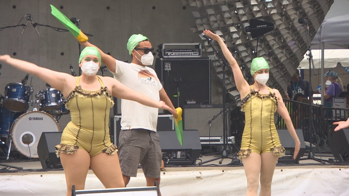 Two women and a man wearing masks are seen posing.