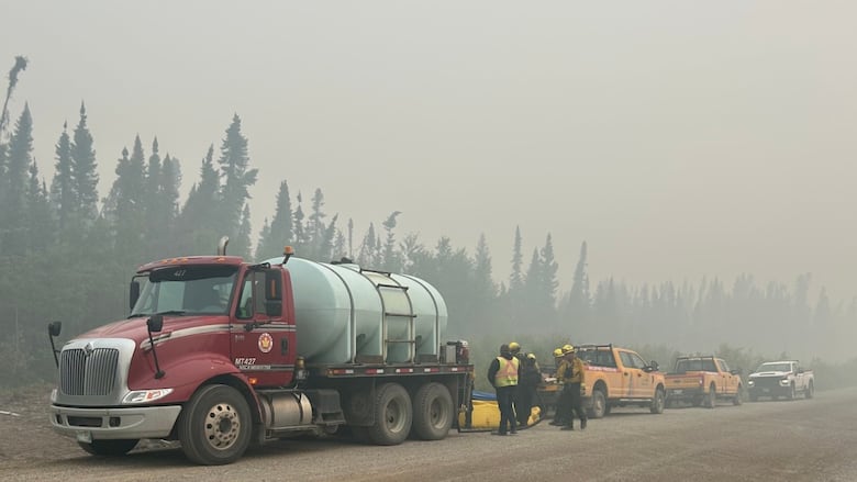 A smoky sky over a forest with work crews on a road.