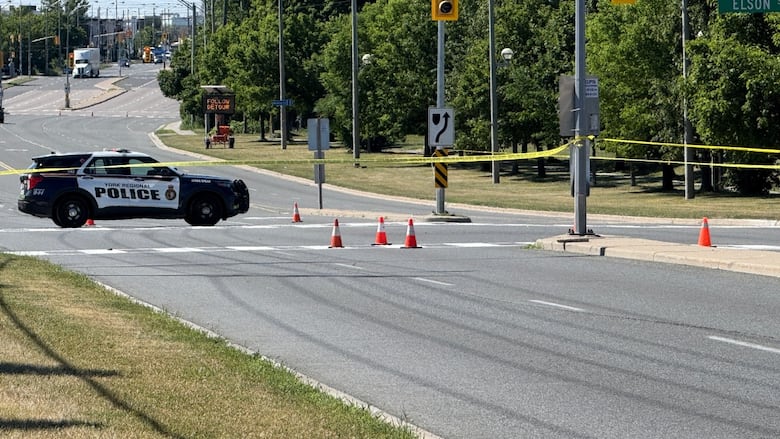 Photo showing a police car on a road behind yellow police tape
