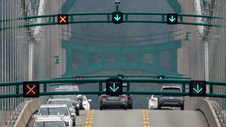 Cars are pictured driving on a bridge with two lanes having a green arrow and one having a red x. 