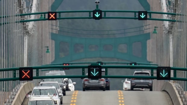 Cars are pictured driving on a bridge with two lanes having a green arrow and one having a red x. 