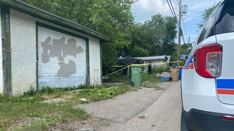 A police officer behind yellow police tape next to a black tent covering the scene of a fatal police shooting.