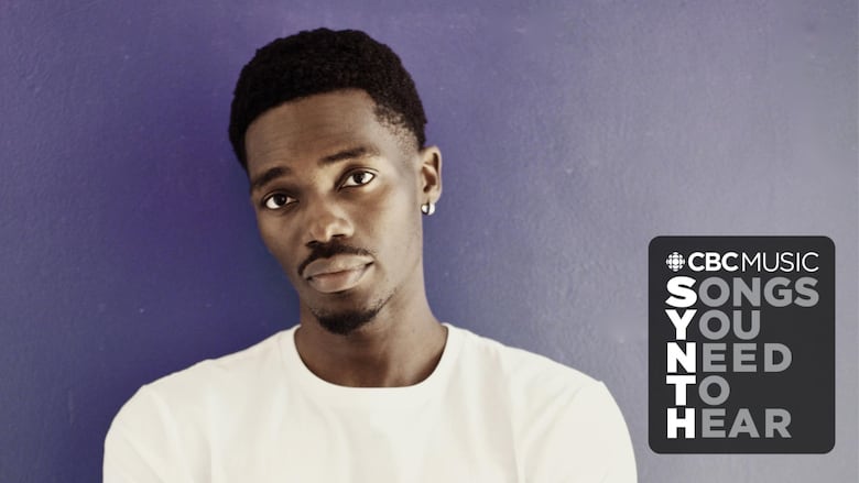 A photo of Tobi (a Black man) standing in front of a purple wall. 
