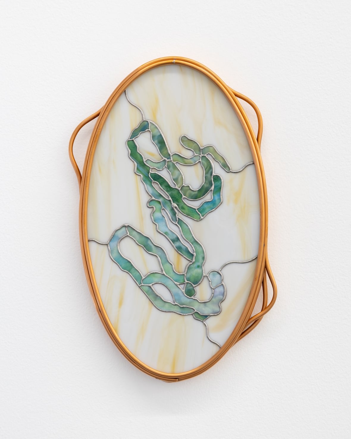 Hanging on a white wall in a copper hoop, a cream-coloured stained glass artwork is marked with a scrawling green line.