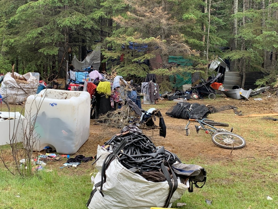 Random things such as a bike, clothings and materials are seen scattered in a section before entering the forest.