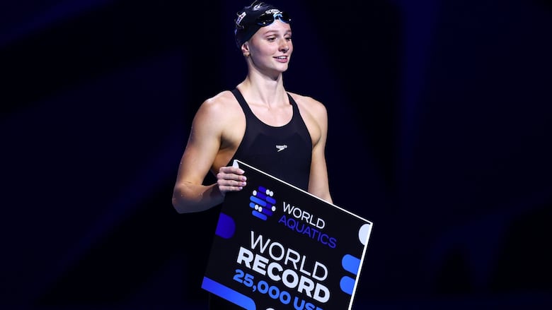 A swimmer holds a world record banner.