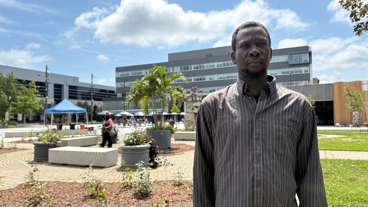 A man in a grey striped dress shirt stands in front of Windsor's new civic esplanade.