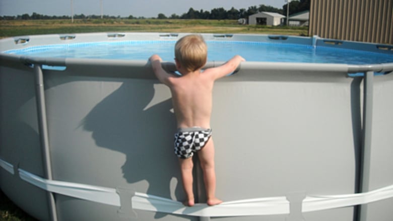 A young child climbing up the side of an above-ground pool