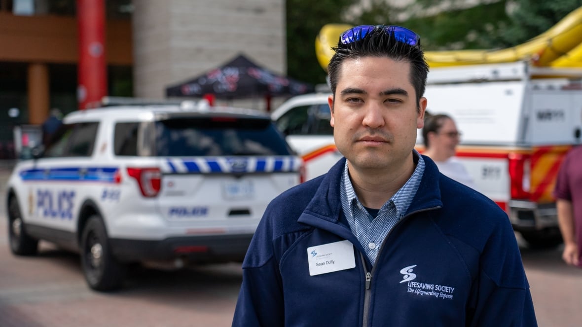 Man looking at camera. Police Cars in the Background.