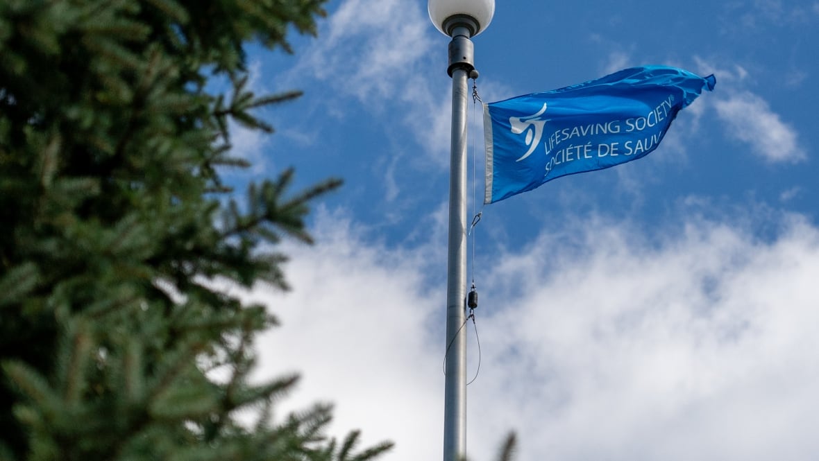 A blue flag flies from a pole. It reads "lifesaving society"