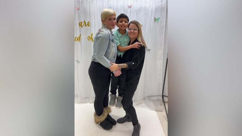 Two women holding a young boy.