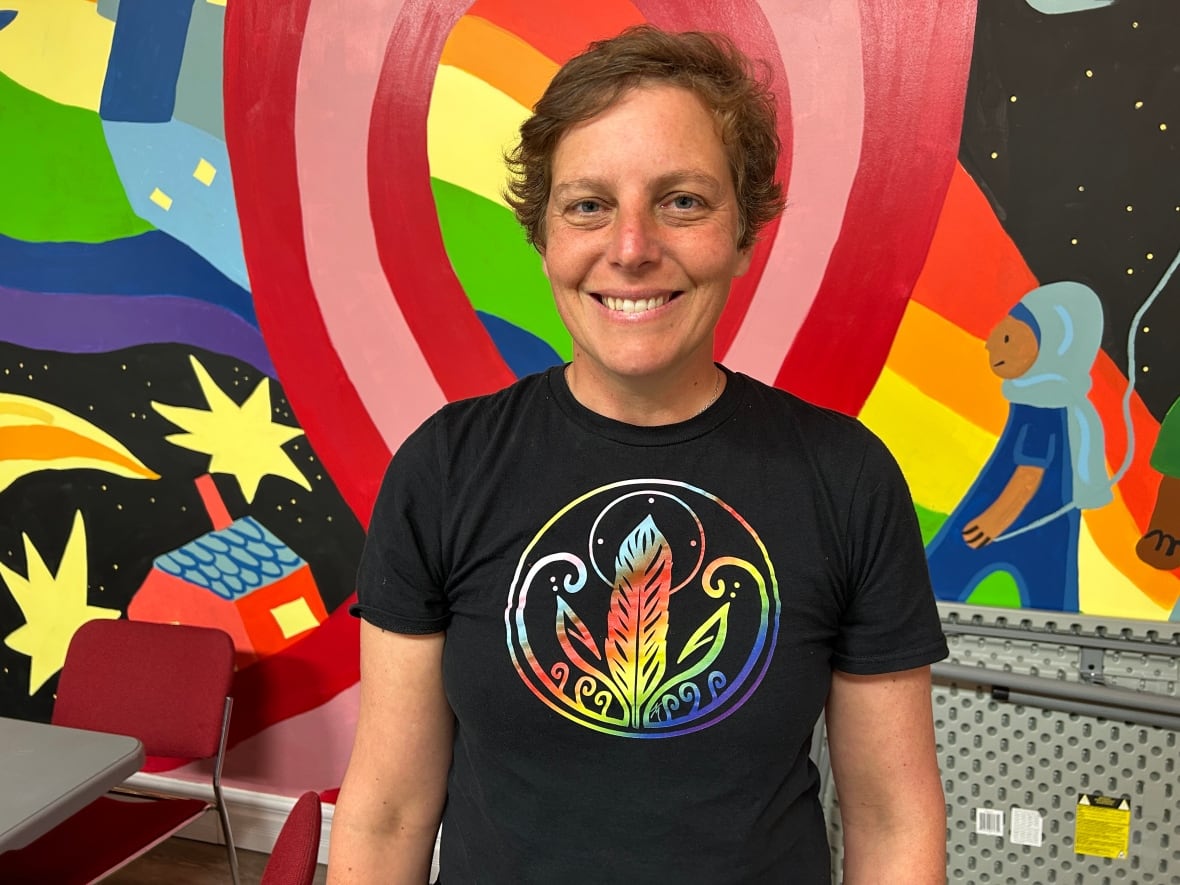 A woman in a black t-shirt smiles and looks at the camera.