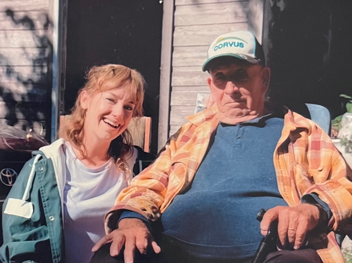 Lindsey Middleton smiling next to Austin Miller (right), wearing a cap and plaid shirt, seated outdoors at his Fort Erie farm.