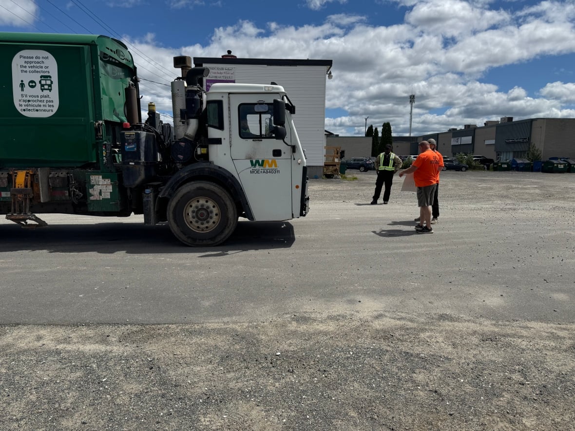 Two men stand and block dump truck from entering.