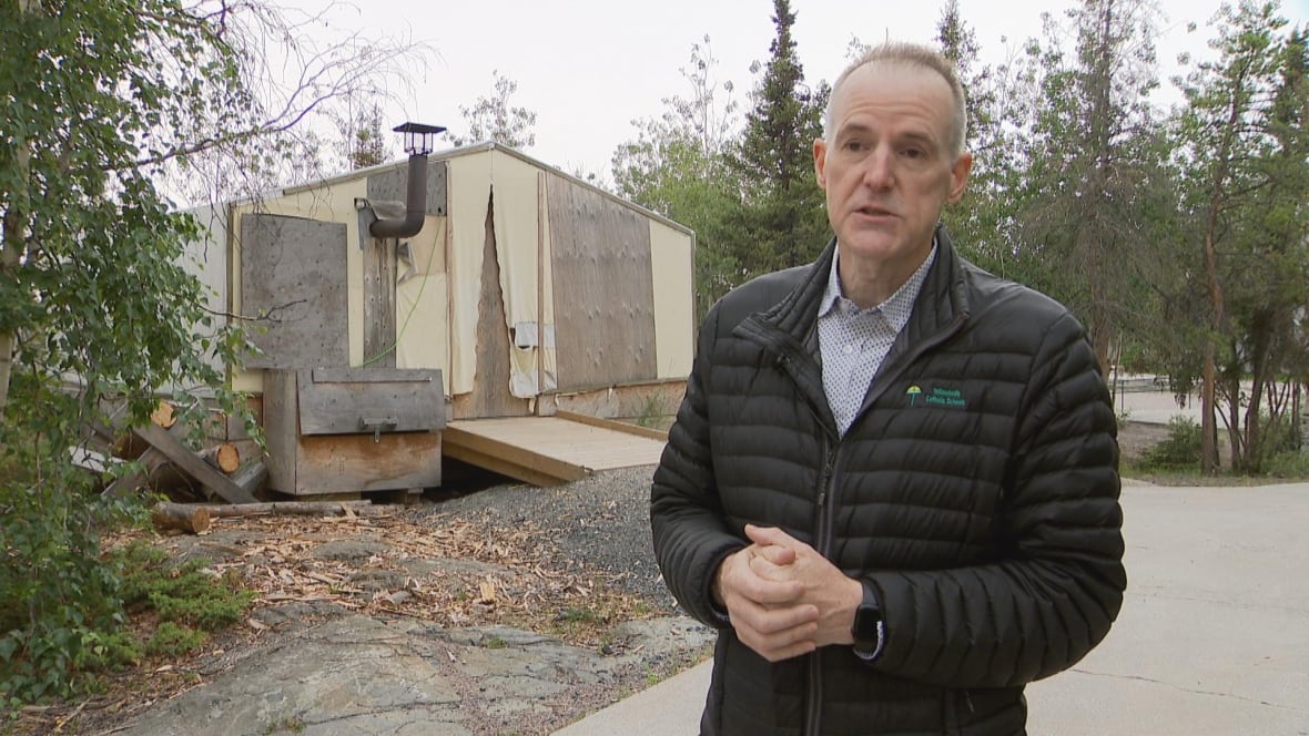 Principal Paul Kelly stands before a tent structure on the school grounds of Weledeh Catholic School. 