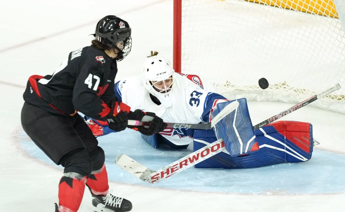 Un portero de hockey estadounidense realiza una parada a un jugador canadiense.