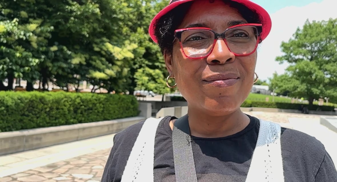 A woman wearing red glasses on a sunny day.