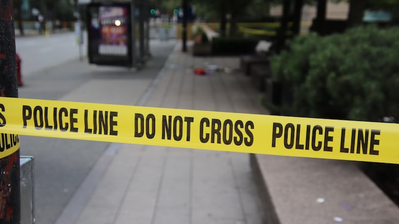 Police tape and a blurry background along a streetscape.