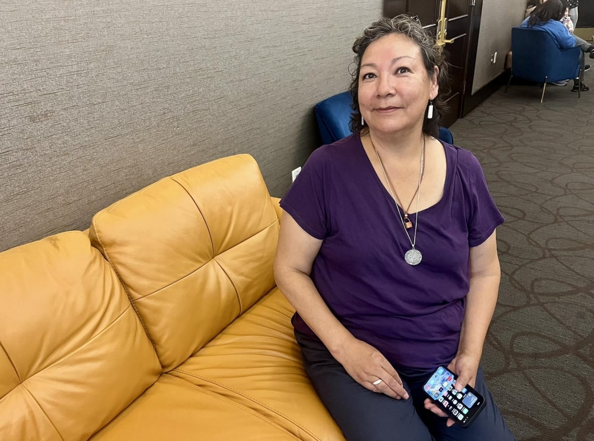 A woman sits holding a cell phone.