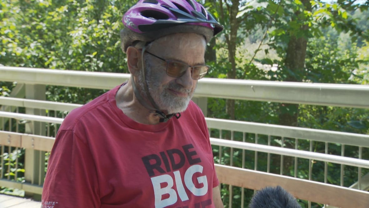 A bicyclist wearing a red T-shirt smiles.