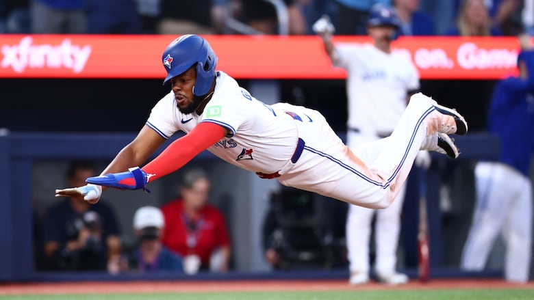 A baseball player dives into home plate.