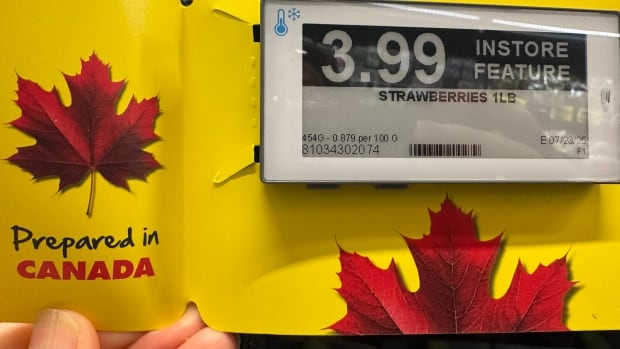 A store sign for strawberries shows a red maple leaf and a'Prepared in Canada," statement.