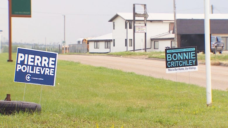 Signs are placed on lawns in front of a rural street.
