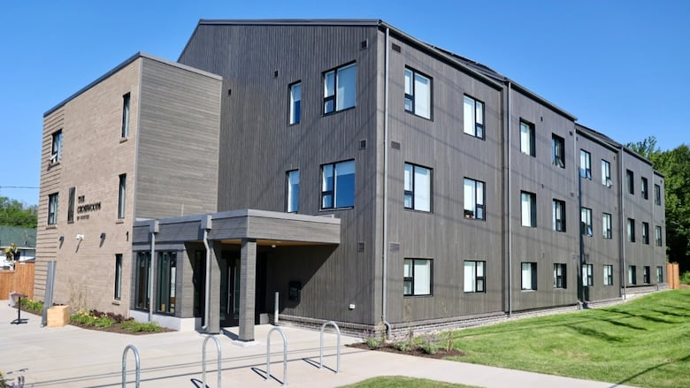 A three-story building with dark grey wood and brick siding.