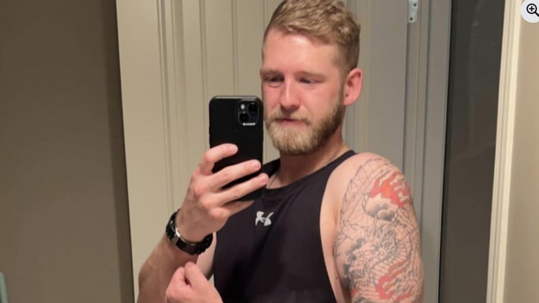 A tattooed man takes a selfie while flexing his arm.