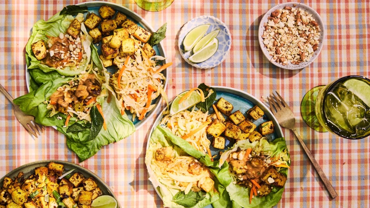 Top down shot of plates of lettuce wraps with vegetable slaw and tofu. They're sitting on a plaid tablecloth.